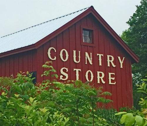 16x20 Barn that has been painted red with a wooden Country Store sign installed on it.