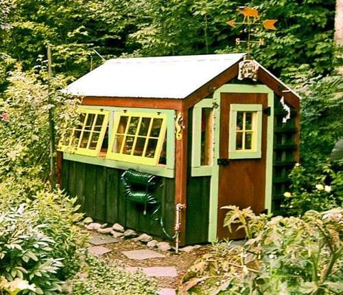 6x8 Greenhouse that has been painted green, yellow and brown with a custom door