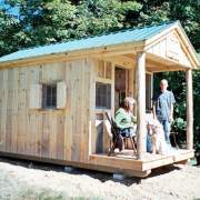 8x16 Bunkhouse with extra windows and screens. A couple with a dog are sitting on the porch
